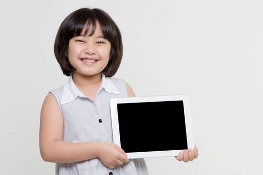 Little Asian Girl Smiling And Holding Tablet Computer