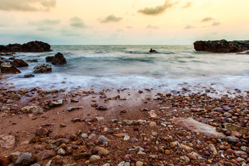 Fototapeta na wymiar Seascape coast of evening wave with rock and cloud on golden sky