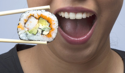 woman bringing sushi with chopsticks to het mouth