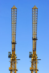 Two construction yellow cranes towers isolated on blue sky