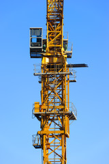 Fototapeta na wymiar Construction yellow crane tower with operator cabin in blue sky
