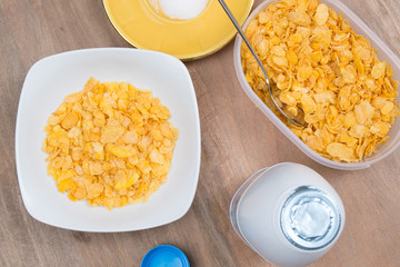 Cornflakes with milk, eggs,  on a wooden brown background