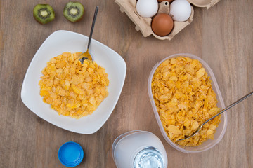 Cornflakes with milk, eggs,  on a wooden brown background