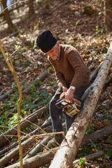 Naklejka premium Old woodcutter at work with chainsaw