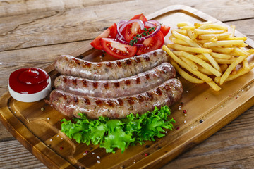 Grilled sausages with french fries on a cutting board