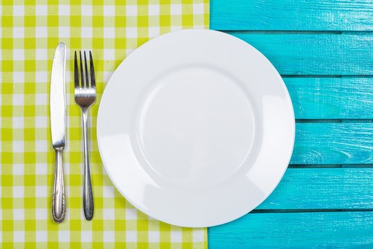 Tablecloth. Empty plate with fork and knife on tablecloth over