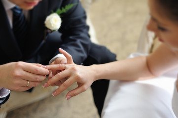 Obraz na płótnie Canvas Groom putting ring on bride's finger