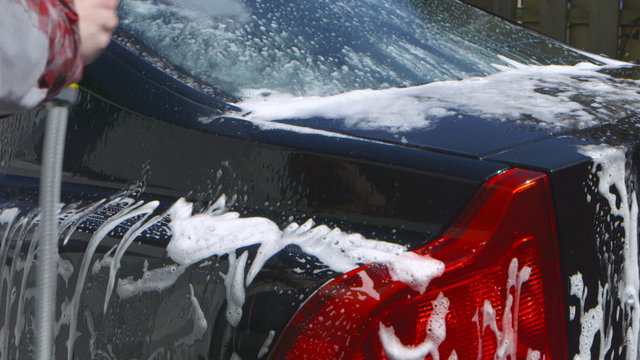 Car Care - Man using a garden spray gun