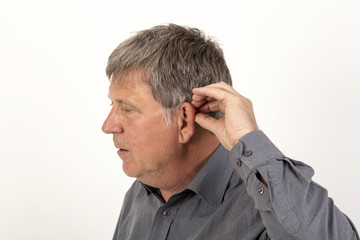 man  puts hearing aid in the ear