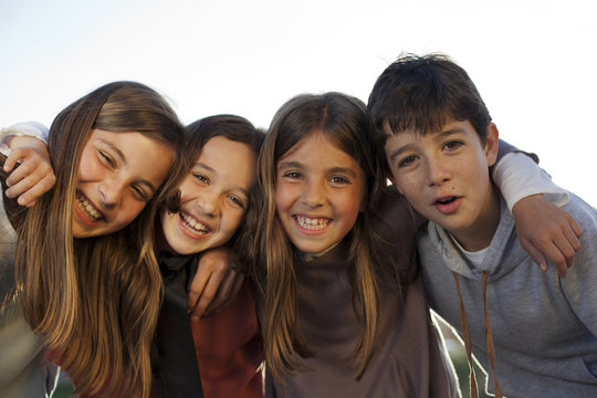 Niñas y niño cogidos por los hombros sonriendo