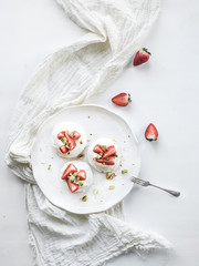 Fototapeta na wymiar Small strawberry and pistachio pavlova meringue cakes with