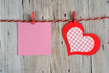 Paper heart and blank note on old wooden background