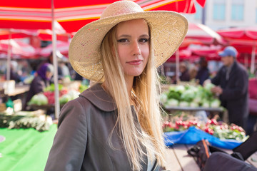 Portrait of attractive blonde girl with straw hat at the market.