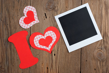 Instant photo and paper letter with hearts on old wooden table