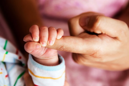 Newborn baby holding father hand