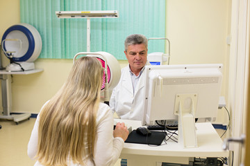 Young woman having her eyes examined by an eye handsome elderly
