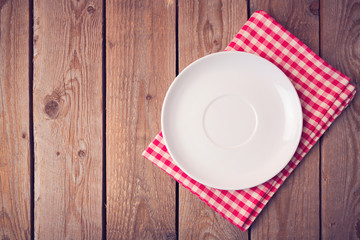 Plate on checked tablecloth over wooden background