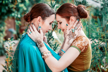 Two beautiful girls in the Indian national bright dress with oriental makeup.
