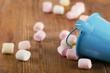 Sweet marshmallows spilling from  a bucket.