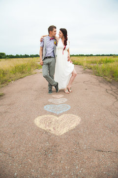 Heart symbols shaped with crayons on ground and two people in lo