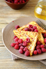 French toast with raspberries and honey on a plate