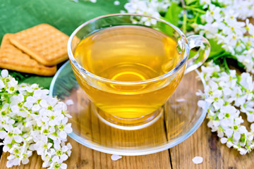 Tea in cup with cookies and flowers of bird cherry on board