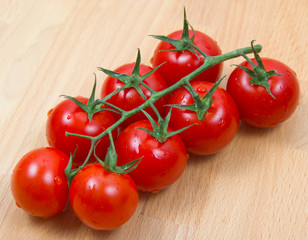 Tomatoes cherry civered by water drops on a wooden board