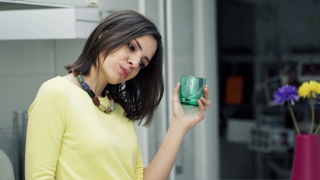 Sad, unhappy woman drinking water standing in kitchen at home