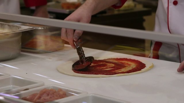 Applying  tomato sauce on original Italian raw pizza, dough