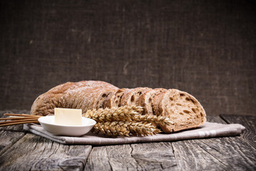 Tasty bread with wheat on wooden background.