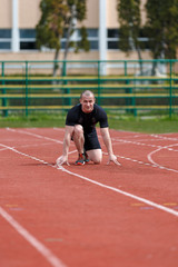 Obraz premium muscular athlete is at the start of the treadmill at the stadium