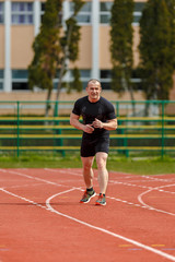 Obraz premium muscular athlete is at the start of the treadmill at the stadium