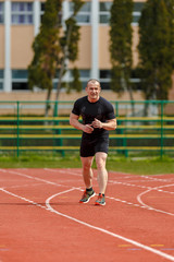 muscular athlete is at the start of the treadmill at the stadium