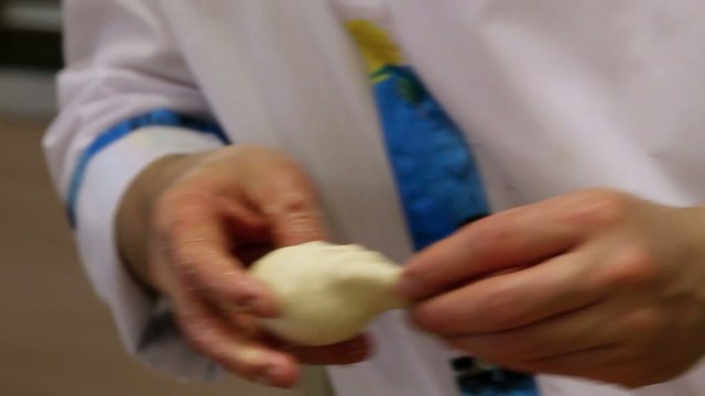 Chef preparing dough with rolling pin for asian food on wooden