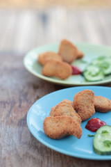 Chicken nuggets with sliced cucumber and ketchup.