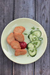 Chicken nuggets with sliced cucumber and ketchup.