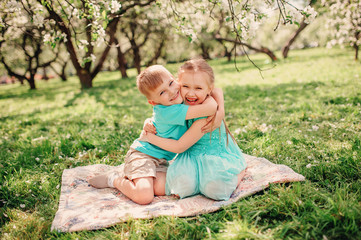 happy brother and sister having fun in spring apple garden