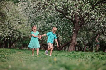 Obraz premium dwoje przyjaciół dziecko spaceru w ogrodzie jabłoni wiosną