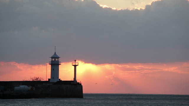 Seagulls fly over a beacon during sunrise, Yalta, Crimea