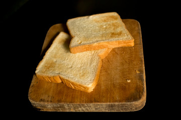 Sliced toast on chopping wood block and isolated on black background