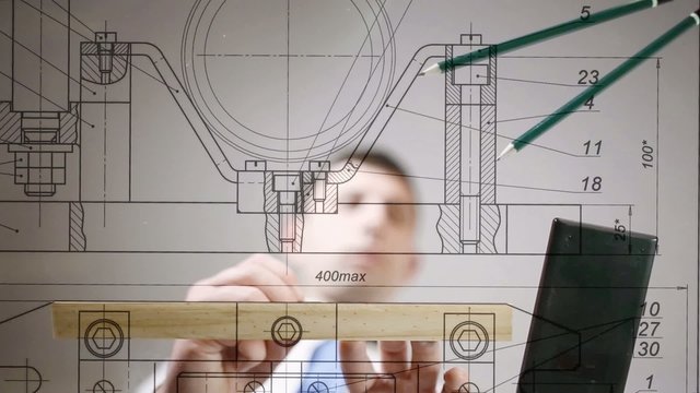 Drawings are on the desktop, hands of engineer drawing by pencil