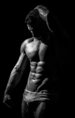 black and white studio shoot of strong athletic man on dark back