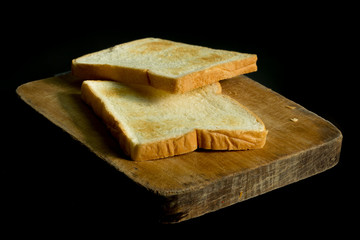 Sliced toast on chopping wood block and isolated on black background