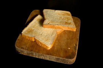 Sliced toast on chopping wood block and isolated on black background