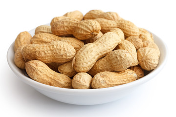 Round ceramic bowl of peanuts in shells. In perspective.