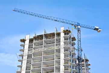Crane and building construction site against blue sky