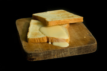 Sliced toast on chopping wood block and isolated on black background