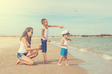 Naklejka premium Mother and her two sons having fun on the beach