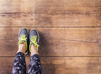 Young runner sitting on floor. Studio shot on wooden background