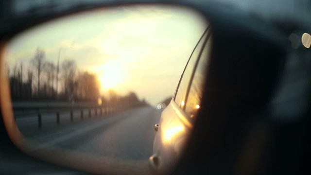 View of the road in the rearview mirror at sunset